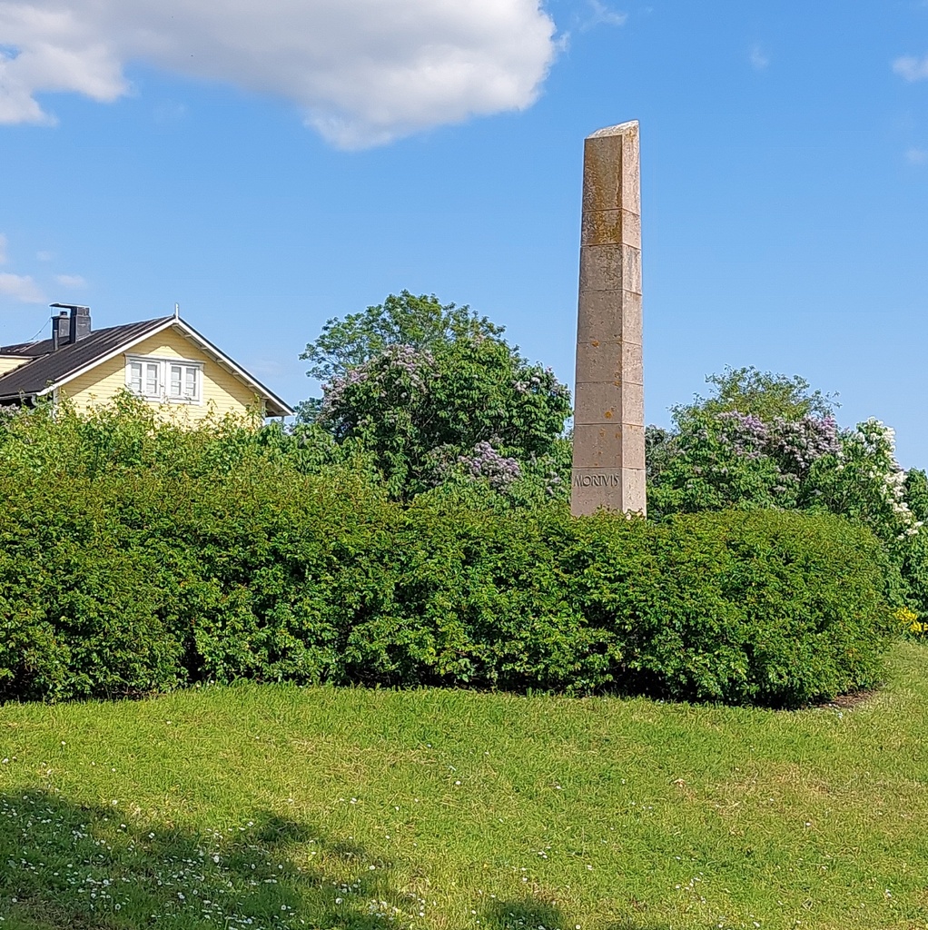 Suomenlinna, Susisaari. Mies valokuvaa Linnoituksessa menehtyneiden muistomerkkiä. Arkkitehti Elsi Borgin suunnittelema obeliskimainen muistokivi Mortuis (kuolleille, menehtyneille) on pystytetty 1951 Suomenlinnassa eri katastrofeissa menehtyneiden muistoksi. Muistomerkkiin on kaiverrettu vuosiluvut 1808, 1855, 1906, 1917, 1918, 1937 ja se on sijoitettu Vallisaaren räjähdysonnettomuuden uhrien hautapaikalle Piiperin puiston itäpuolelle. rephoto