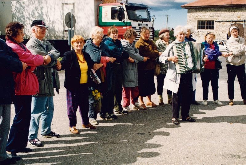 Eesti Geograafia Seltsi Muhu- ja Saaremaa (21.-24.08) ekskursioonist osavõtjad Kuivastu sadamas lahkumislaulu laulmas. Vasakult: Aino Miilmets, Asmu Saar, reisi juht Urve Kirss, Elin Kadai, Tiiu Saarist, ..., Aino Taho, Laine Merikalju, Heljo Ader, Linda Jeeser ja Iiri Kitsing; keskel Elle Lees akordioniga.
