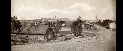 Paremal heleda otsaseinaga praegune Tartu maantee 73, (valmis 1881, arh Nikolai Thamm, 1900ndate alguses saanud juurde- ja ümberehituse) Brandmanni saunana tuntud elu- ja ärihoone (Tartu maantee saun).
✅ Järgmisena, puudesalust paistmas selle kandi üks vanemaid puithooneid, Tartu mnt 69. Oliver Orro sõnul üks piirkonna vanimaid hooneid, asustus- ja linnaehitusajaloolise väärtusega kui haruldane näide Tartu postimaantee vanast, praegusele kihistusele eelnenud hoonestusest. Üksikehitisena huvitav Tallinna puitarhitektuuris ainulaadse külgfassaadi galeriiveranda tõttu. 1856 a kaardil maja kenasti olemas, kinnituregistris on esimene saadaolev sissekanne 29.05.1864, kui kinnistu omandas tisler Conrad G. Sporleder.
*Kas vasakul, praeguse Odra-Lastekodu ristil näha olev kaarakendega kivimaja võib olla Lastekodu 31, kunagise Düüna rügemendiga seotud hoone?
✅ Aga mäest alla vasakul tänapäeval muidugi Liviko kompleks, piiritulp tundub olevat tänase Odra tn otsa kohal.  duplicate photo