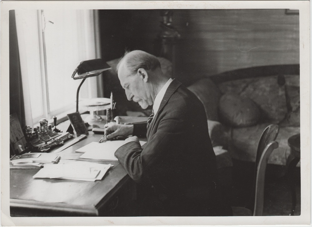 Jaan Tõnisson kirjutuslaua taga pabereid uurimas.