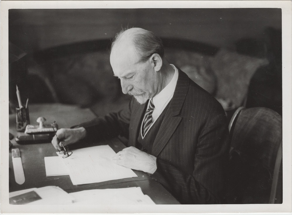 Jaan Tõnisson kirjutuslaua taga pabereid uurimas.