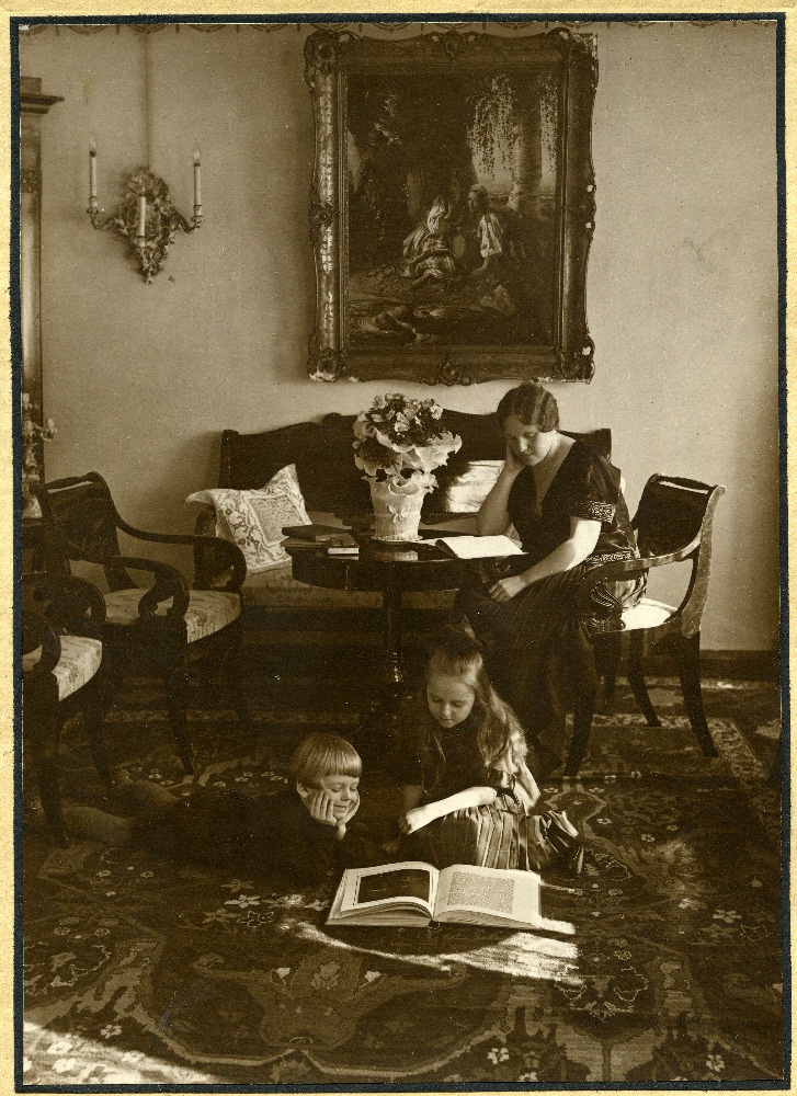 Hilda Tõnisson laua taga lugemas, Lembit Rein ja Hilja Tõnisson vaibal raamatut uurimas