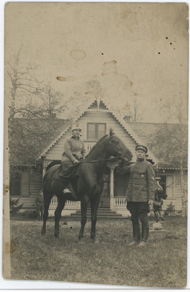 Naisterahvas hobusel, meesterahvas kõrval, taustal taluhoone