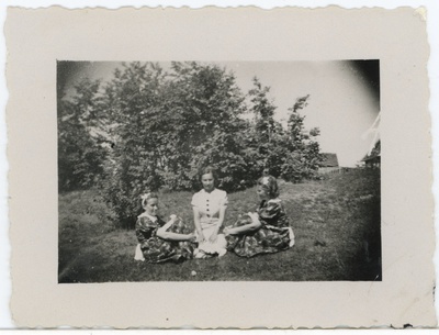 Kolm määratlemata noort naist põõsaste taustal istumas  duplicate photo