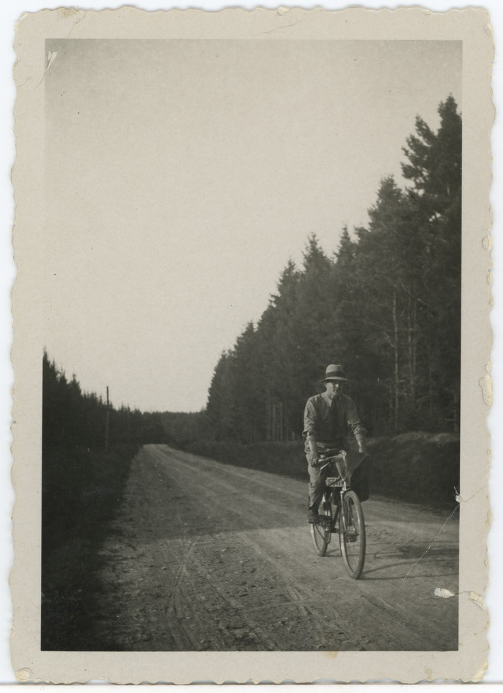 Noormees jalgrattaga metsavahelisel teel sõitmas