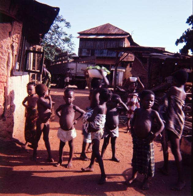 Group of village children on the road next to the building; situation picture