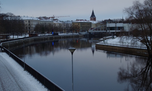 Tartu kesklinn Emajõe parem- ja vasakkaldal. 
Esiplaanil Emajõe üleveoparv Uueturu ja Holmi t joonel. Taga Kivisild.
Paremal hotelli "Jakor" hoone ( juugendstiil, arh. R. von Engelhardt, 1905), eemal kino "Illusion" hoone. Vasakul lodjad. 
Tartu, ca 1910. rephoto