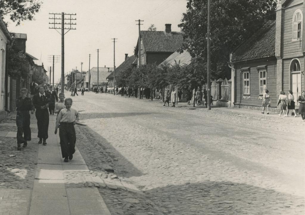 Foto Võrumaa laulupäeva rongkäigus osalised liikmumas staadioni poole, rahvas möödumas Kreutzwaldi tänaval Killomani  ja Kreutzwaldi memoriaalmuuseumi majast 9.juulil 1950.a.