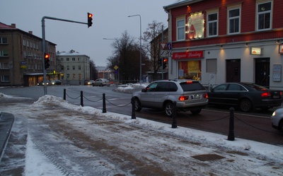 Postijaama plats Riia mäel.
Esiplaanil puuputkad ja hobuvankrid mitmesuguse kraamiga. Paremal pool (Pihkva t; hilisem Võru mnt) asetsevatel majadel eesti- ja venekeelsed sildid: Vürtsi kauplus; Õlle pood
Vaade postijaama poolt kesklinna suunas.  Tartu, 20. saj. algus. rephoto