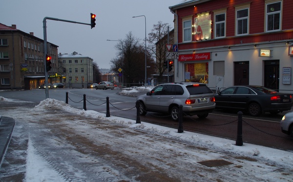 Postijaama plats Riia mäel.
Esiplaanil puuputkad ja hobuvankrid mitmesuguse kraamiga. Paremal pool (Pihkva t; hilisem Võru mnt) asetsevatel majadel eesti- ja venekeelsed sildid: Vürtsi kauplus; Õlle pood
Vaade postijaama poolt kesklinna suunas.  Tartu, 20. saj. algus. rephoto