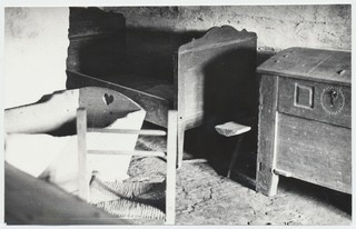 Eeru kõrtsi tagakamber: näha puuvoodi, riidekirst, häll, puupink ja õlgpõhjaga tool