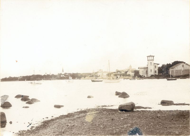 Foto. Haapsalu Suure Promenaadi vaade Vanasadamast. Esiplaanil laohoone, mitmesugused veesõidukid, Ungern-Sternbergi villa. U 1890.