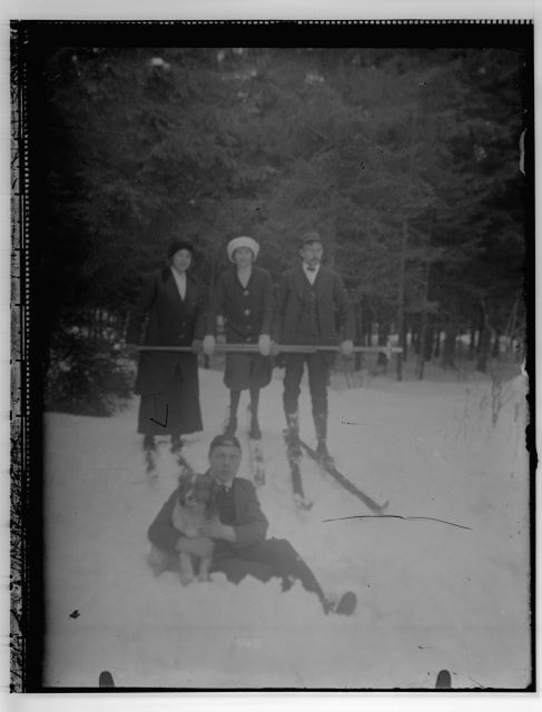 Grupifoto, talvises metsas suuskade ja koeraga