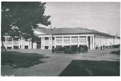 Kaubahoov (Barclay platsi poolne ja Kauba t poolne fassaad). Poodide reklaamsildid: Saapa kauplus. Ludwig Oja;  Moe, pudu ja pesuäri. Vennad Lepp; Moodsaid kleidiriideid. H. Baumann.
Autod tänaval. Tartu, ca 1934.  duplicate photo