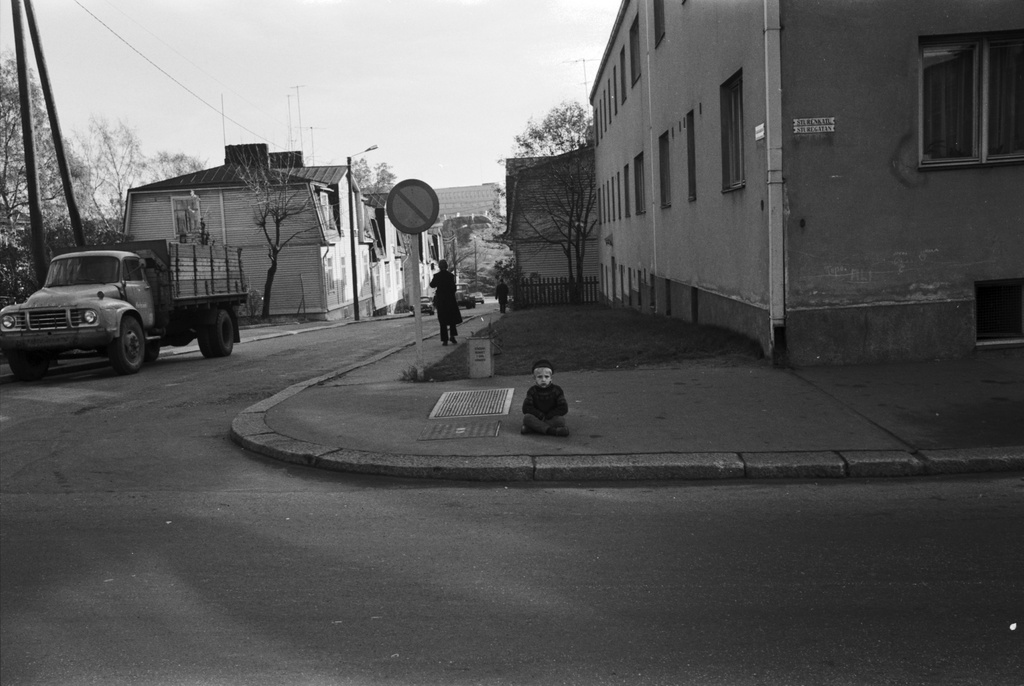 A small boy sits on the foot corridor at the corner of Sturenkadu and Virtaintie