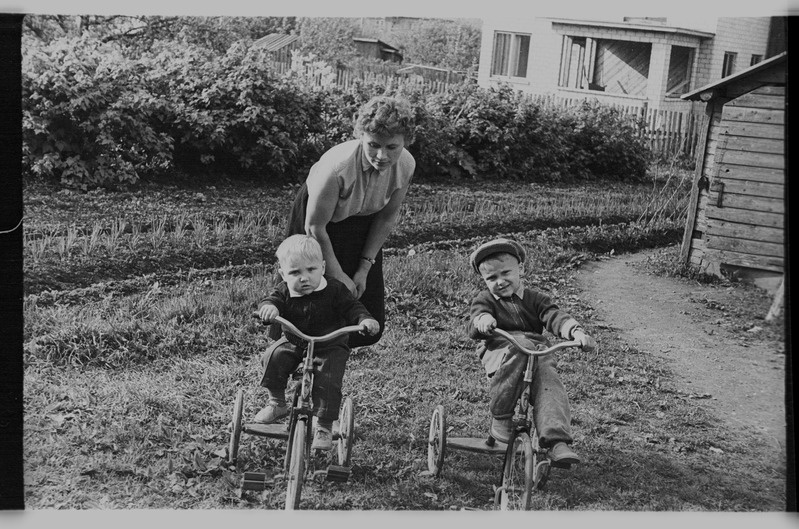 Ema ja jalgratastega pojad aias peenarde juures