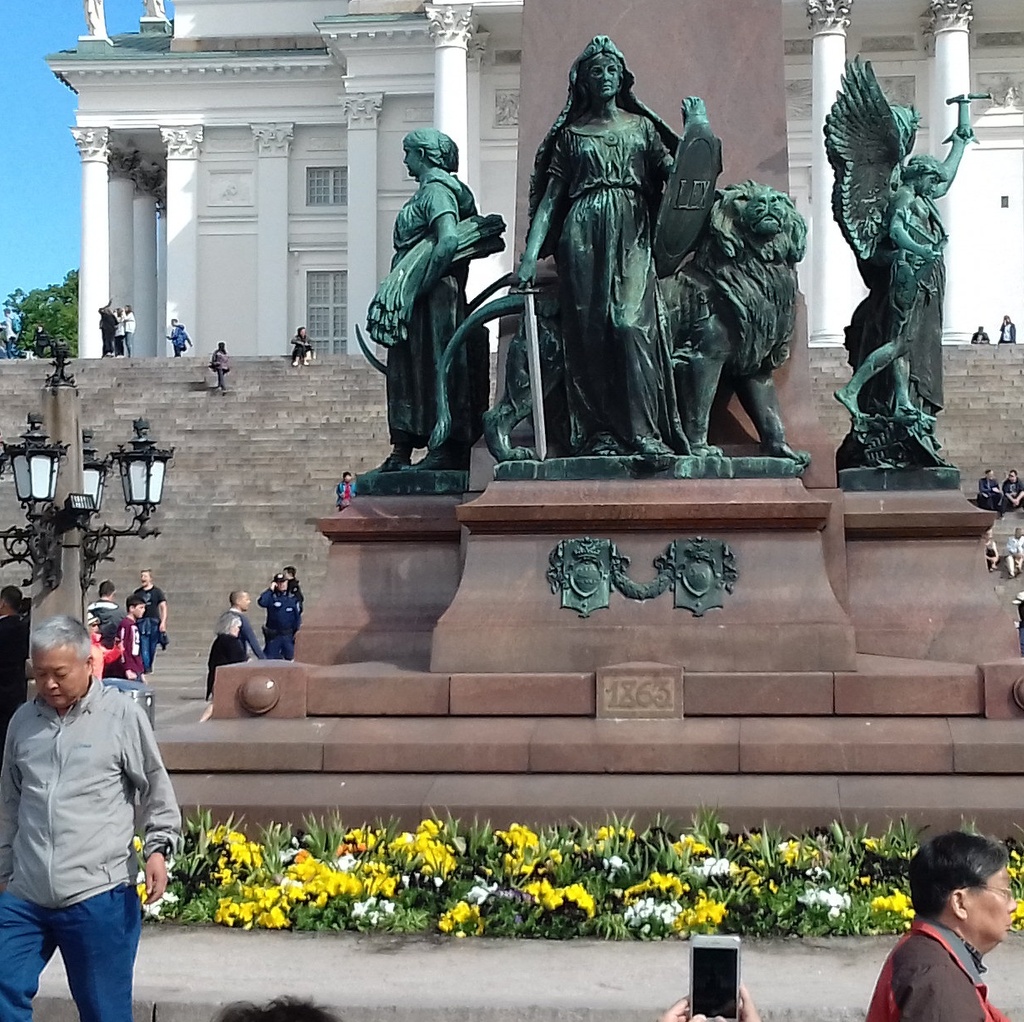 Kommunistien vappujuhla Senaatintorilla. Ihmisiä istumassa Aleksanteri II:n patsaan juurella. rephoto