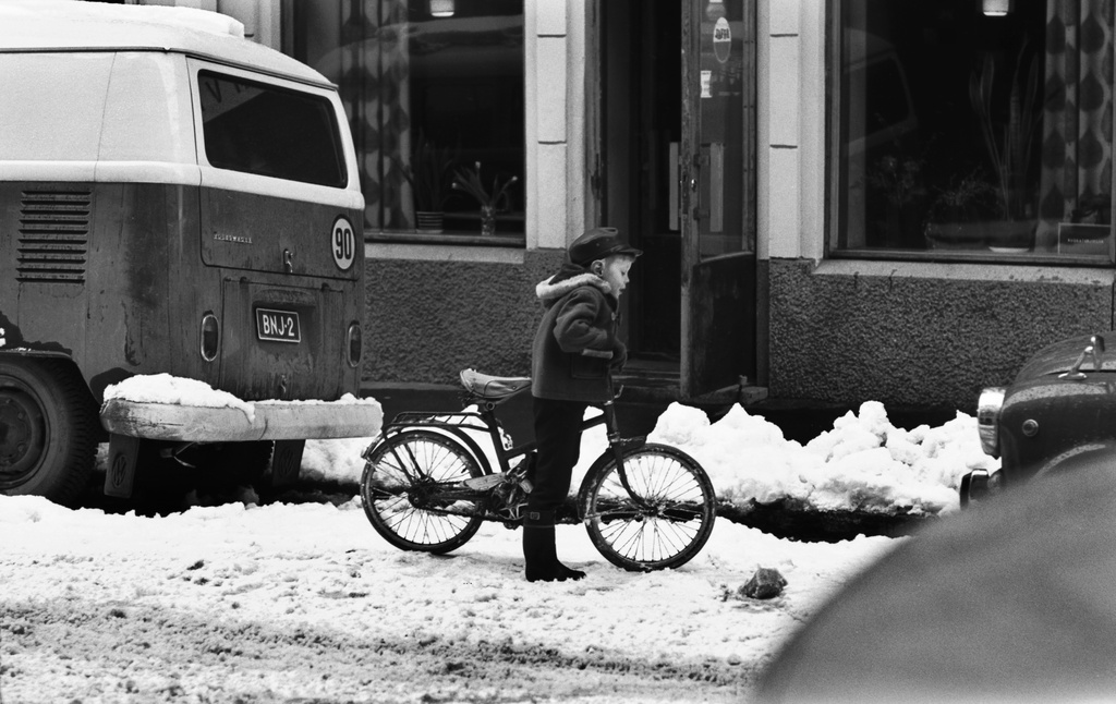 Liisankatu? Poika pienen polkupyörän kanssa autojen välissä lumisella Liisankadulla?.