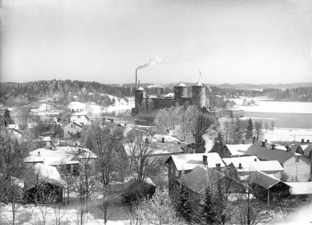 Näkymä Nälkälinnan tornista itäkaakkoon. Etualalla paljon puutaloja Linnankadun, Eerikinkadun ja Akselinkadun varrella. Keskellä Olavinlinna. Taustalla vasemmalla Kyrönniemi. talvi 1949–1950-luku. View east-southeast from Nälkälinna