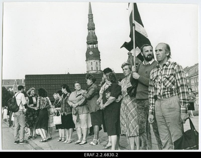 Baltic chain on the territory of Latvia. People waving flags. The tower of the Riga Peetri Church looks behind  duplicate photo
