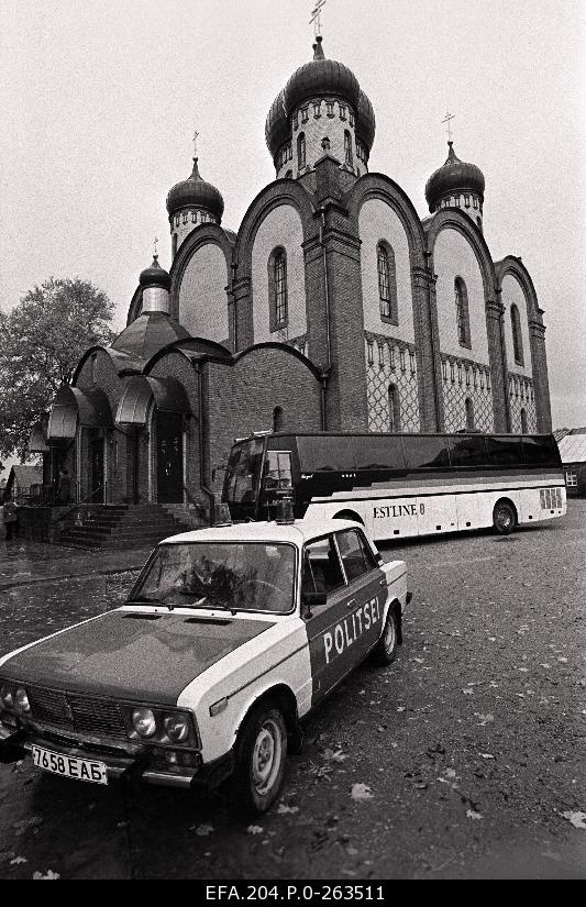 Diplomatic transporting bus and escort police car At the yard of the Kuremäe Monastery of the Almighty Lady of Almighty Sleeping (Uspenski) in the back of the Archbishop of the Almighty Lady of Almighty.