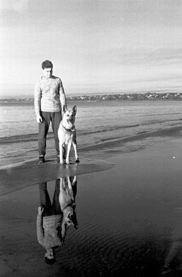 Mees koeraga rannal seismas.  similar photo