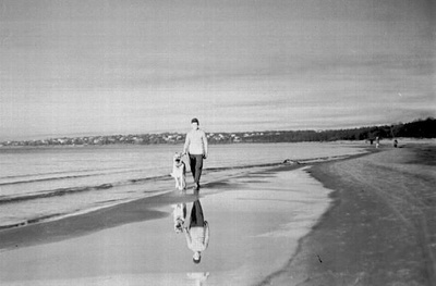 Mees koeraga rannal seismas.  similar photo