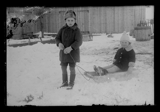 Laste talvine rõivastus - poiss ja tüdruk kelguga