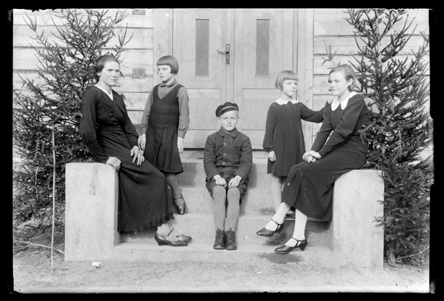 Naiste ja laste rõivastus - maja trepil pidulikes riietes lapsed ja naised (õpetajad õpilastega ?)