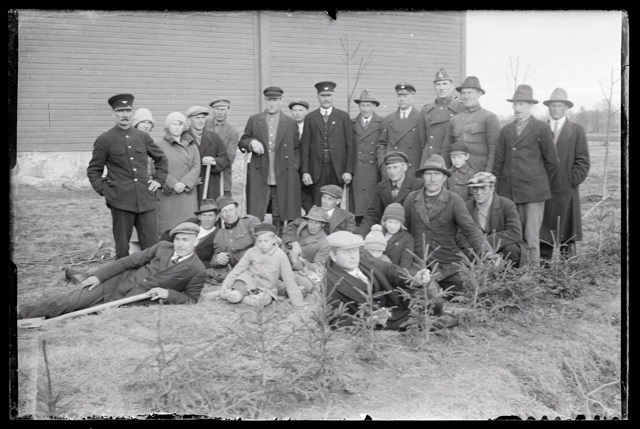 Puude istutamine ? - mehi, naisi ja lapsi labidatega noorte istikutega poseerimas