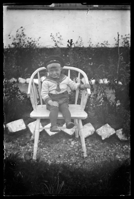 Laste rõivastus - madrusestiilis riietega väike poiss aias toolil