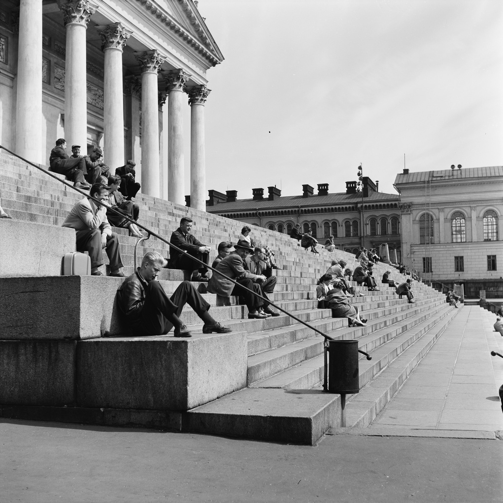Kaupunkilaisia istumassa Tuomiokirkon portailla.