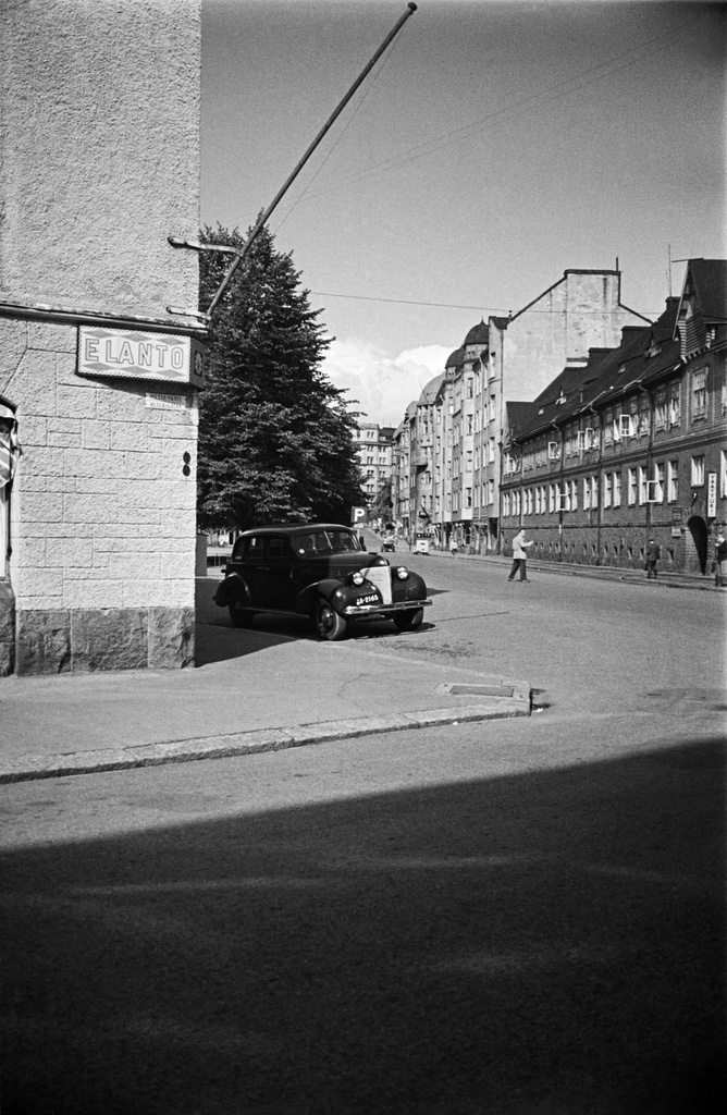 Näkymä Pietarinkadulta pohjoiseen pitkin Kapteeninkatua, oikealla Kapteeninkatu 7, 9. Vasemmalla talon seinässä Elannon kyltti, oikealla vaatturiliike.