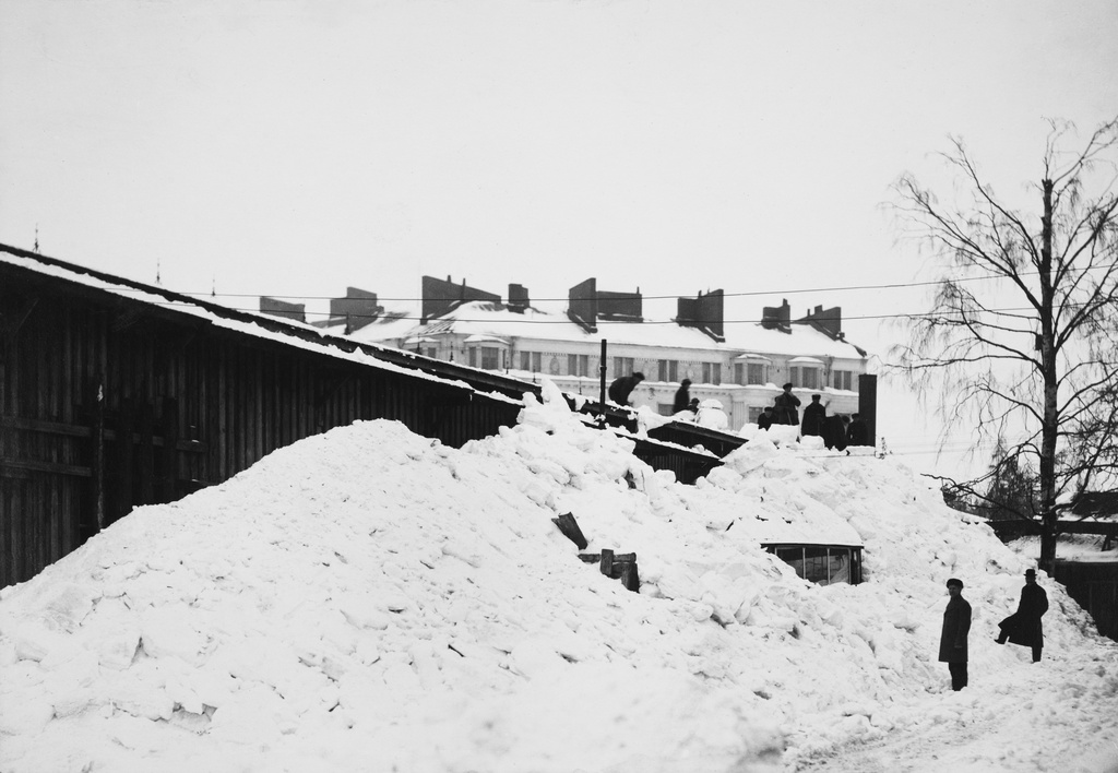 Lumen luontia Raitiotie- ja Omnibusosakeyhtiön Töölön varikon katolla. Romutettavan raitiovaunun kori näkyvissä lumen alta.