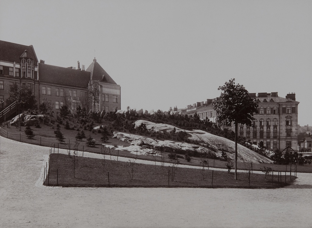 Johanneksen kirkon kalliopuutarha. Taustalla vasemmalla Johanneksentie 4 ja 6, oikealla Laivurinrinne 2.