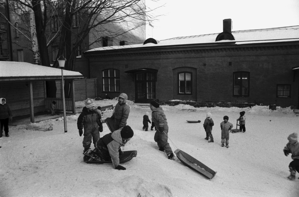 Aleksanterinkatu 1. Lapsia laskemassa pulkalla päiväkoti Aleksin lumisella pihalla.