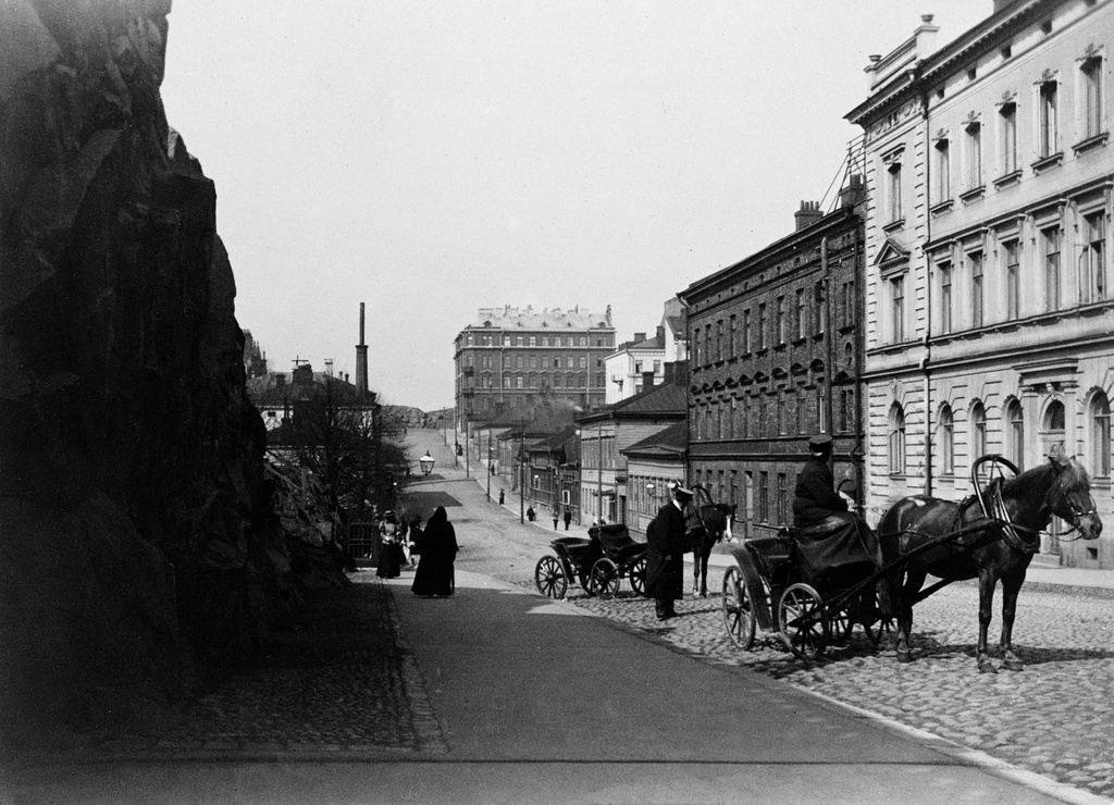 Nikolainkatua pohjoiseenpäin kuvattuna, oikealla Nikolainkatu (= Snellmaninkatu) 17, 19, 21 ja 23, ensinmainittu Vironkadun kulmassa ( - Vironkatu 11).
