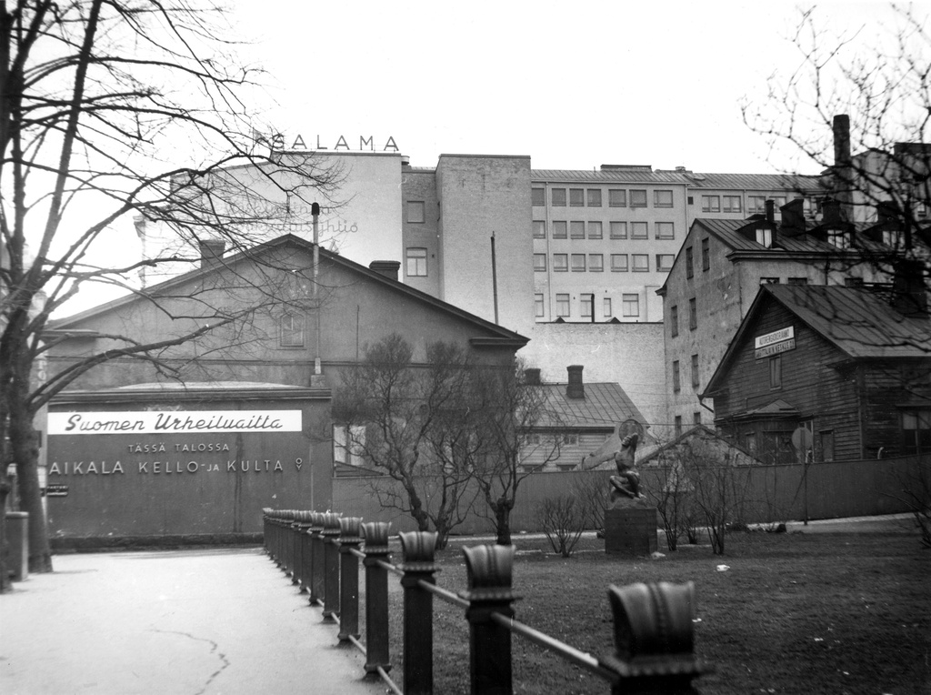 Mikonkatu 8. Taustalla Aleksanterinkatu 15. Kuvassa mainostekstit: Suomen Urheiluaitta, Aikala Kello ja Kulta