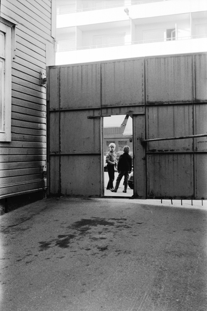Neljäs linja 6, 8. Kaksi poikaa seisomassa kadulla Neljäs linja 6, 8 pihalle johtavan portin edessä. Kuvattu pihan puolelta.