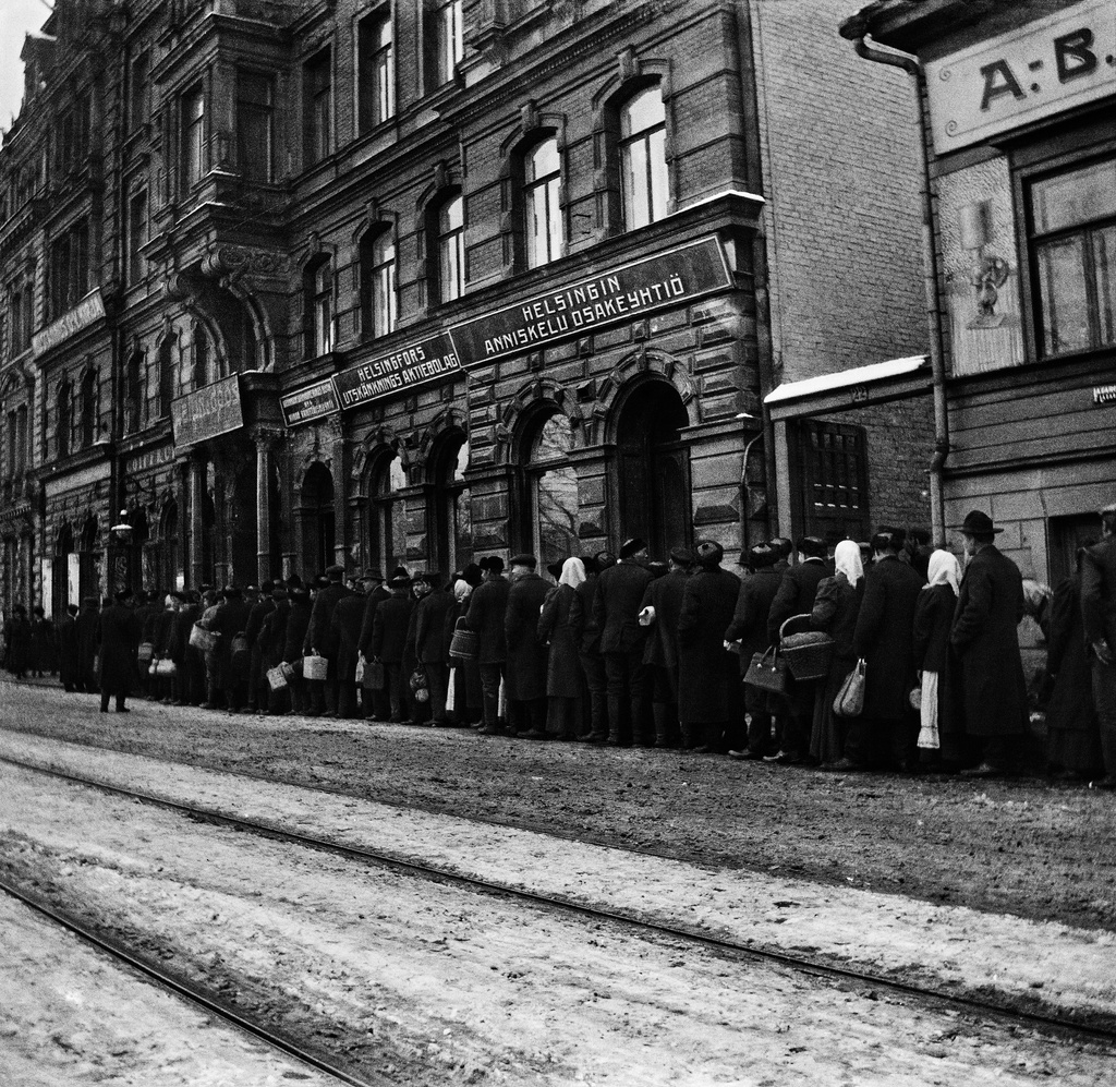 Perunajono Läntinen Heikinkatu 20:n (Mannerheimintie 16) edustalla vuonna 1918. Elintarvikkeiden säännöstely ja jonotus olivat osa kaupunkilaisten arkea poikkeusvuosina.