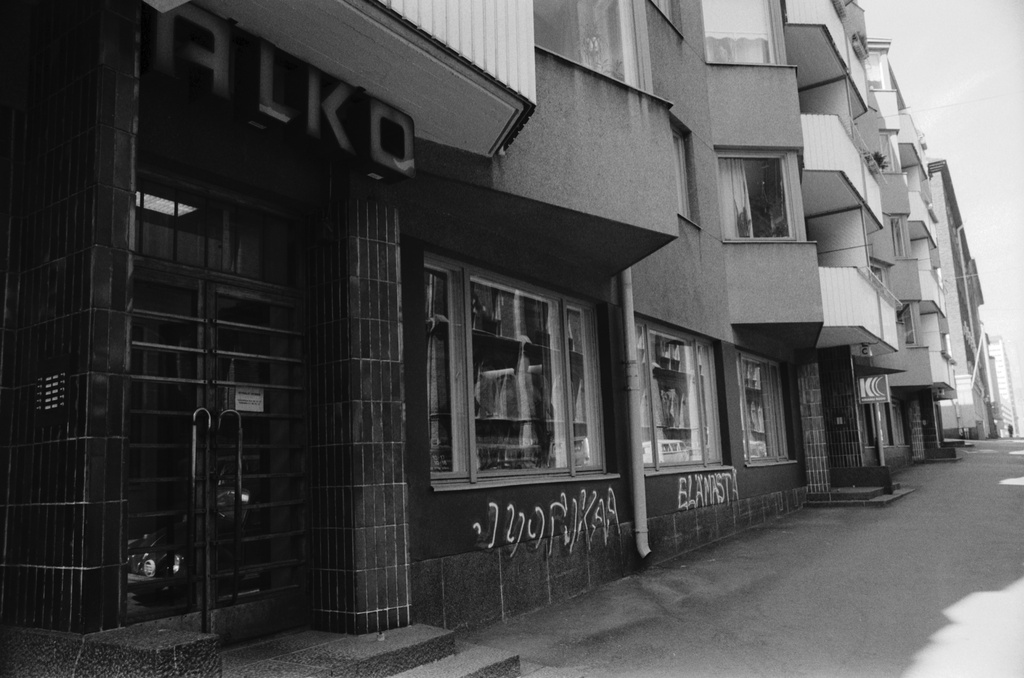 Maurinkatu 8. ALKOn myymälän ovensuuhun maalattu teksti JUOPUKAA ELÄMÄSTÄ Maurinkatu 8:n talon ulkoseinässä. Näkymä Kristianinkadun suuntaan.