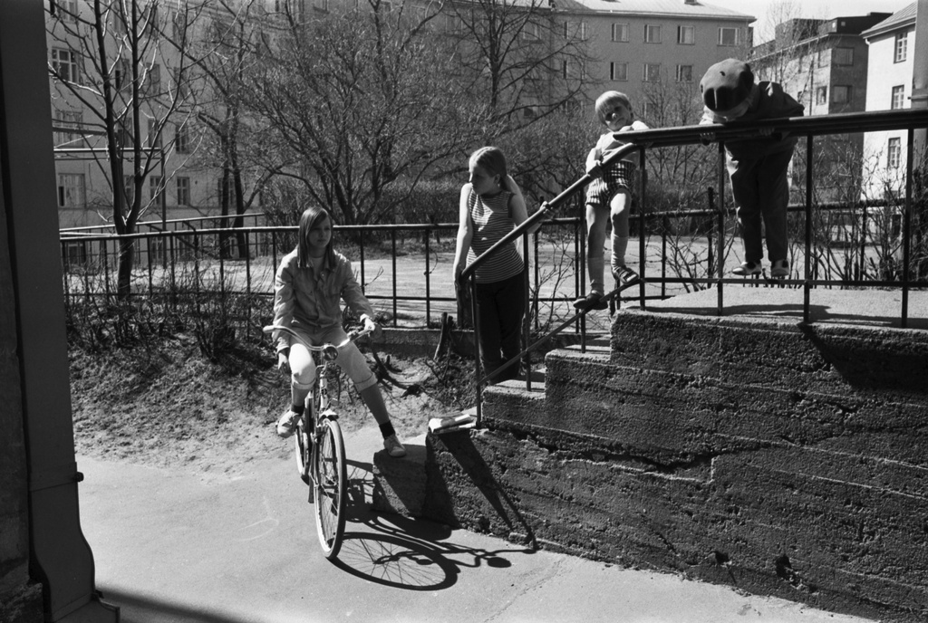 Torkkelinkatu 19. Lapsia keikkumassa portaiden kaiteella kevätauringon paisteessa Torkkelinkatu 19:n pihalla.