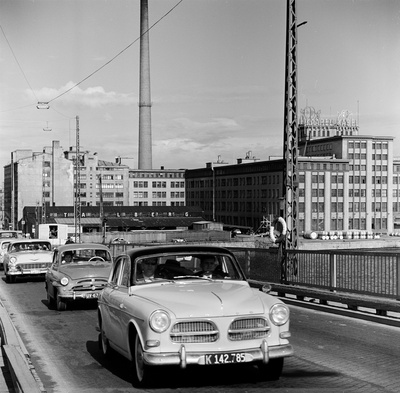 Liikennettä Lauttasaaren sillalla.  Taustalla oikealla Suomen Kaapelitehdas. Myös Julius Tallberg Oy:n varasto näkyy. Ajoneuvot kuvan etualalta taaksepäin lukien: Volvo Amazon, Skoda 440, Chevrolet vm. 1956.  duplicate photo