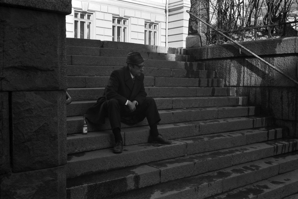Kruununhaka, Liisankatu 13. Mies vieressään alkoholipullo istumassa koulun pihalta kadulle johtavilla portailla Liisankadulla Mariankadun kulmassa.