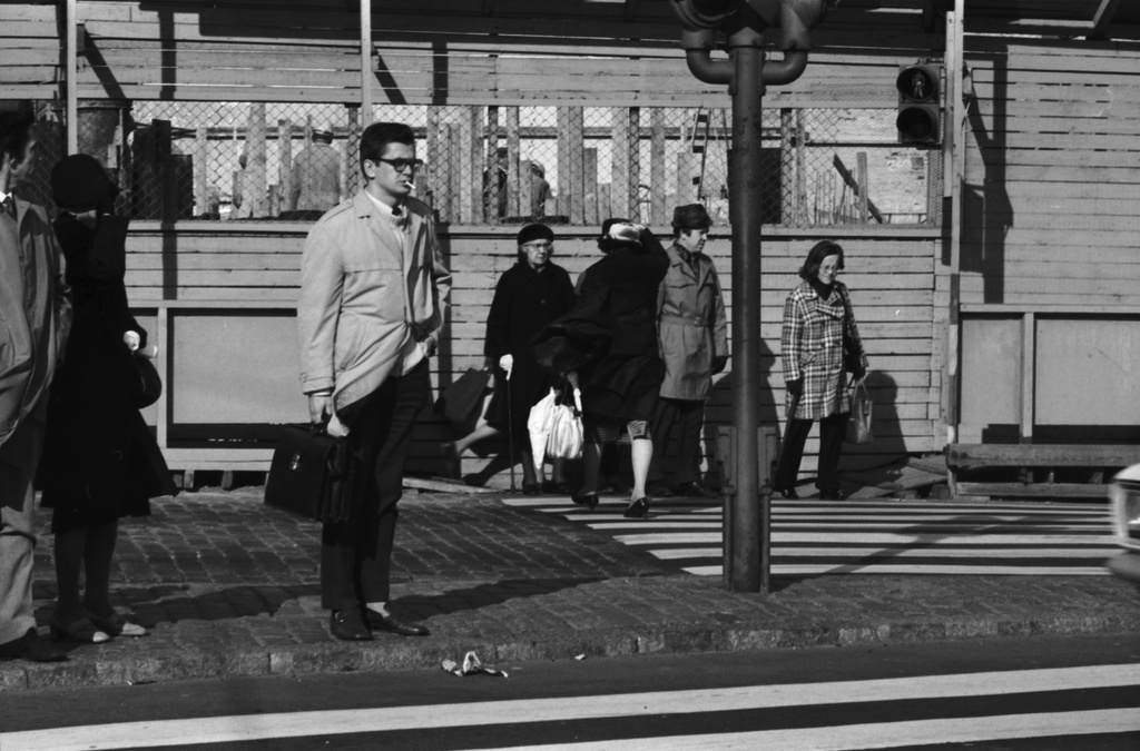 Jalankulkijoita navakassa syystuulessa ylittämässä katua Pohjoisesplanadilla Kauppatorin kulmalla