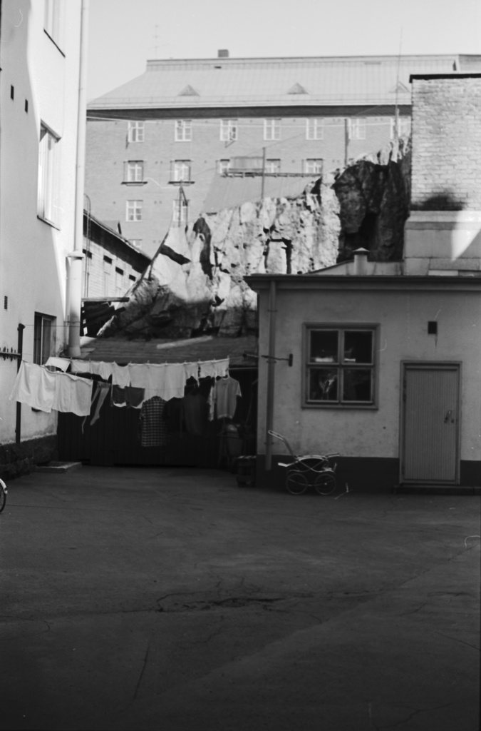 Kaarlenkatu 15. Helsinginkatu 20. Pyykkiä kuivumassa kallion kupeessa olevan pienen piharakennuksen päädyssä kerrostalon pihalla Helsinginkadun - Kaarlenkadun raajaaman korttelin kulmassa
