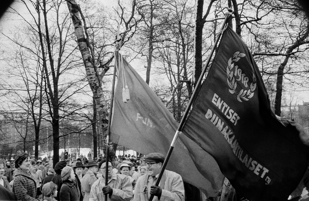 Työväen vappujuhla lumi- ja räntäsateessa Kaisaniemen kentällä 1957. Miehet kantavat mm. Entiset Punakaartilaiset ry:n lippua.