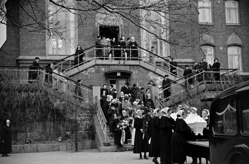 Helsingin Diakonissalaitoksen kirkko, Ester Svenssonin hautajaiset, hautasaatto. Diakonissat nostavat arkkua auton takaosaan.