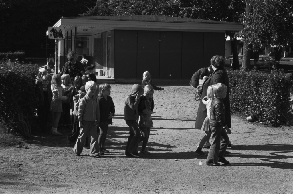 Tehtaanpuisto. Lapsia parijonossa lähdössä hoitajan kanssa Tertaanpuistosta. Taustalla leikkipuiston rakennus.
