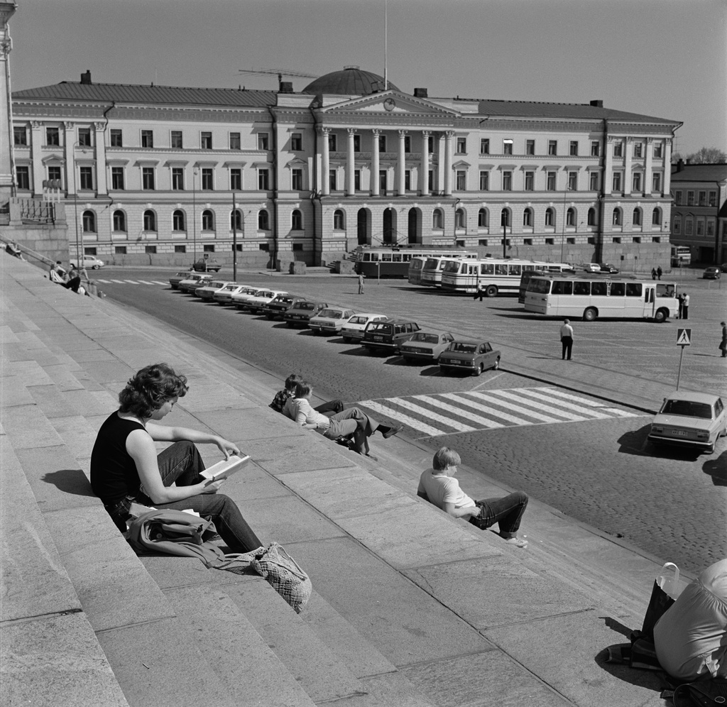 Ihmisiä istumassa Tuomiokirkon portailla.